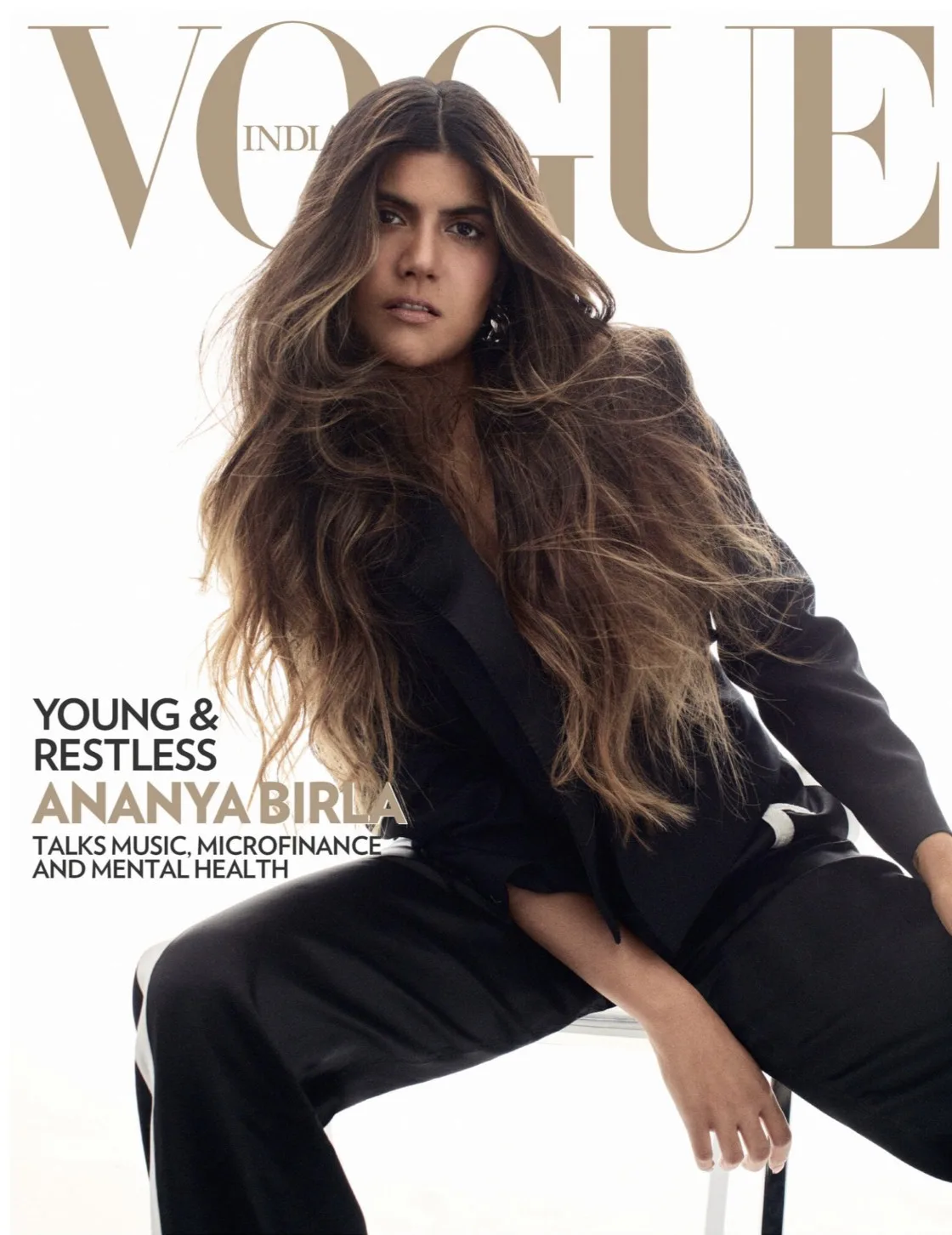 Vogue India cover of Ananya Birla in a black tuxedo suit, long wavy hair, seated on a stool against white.