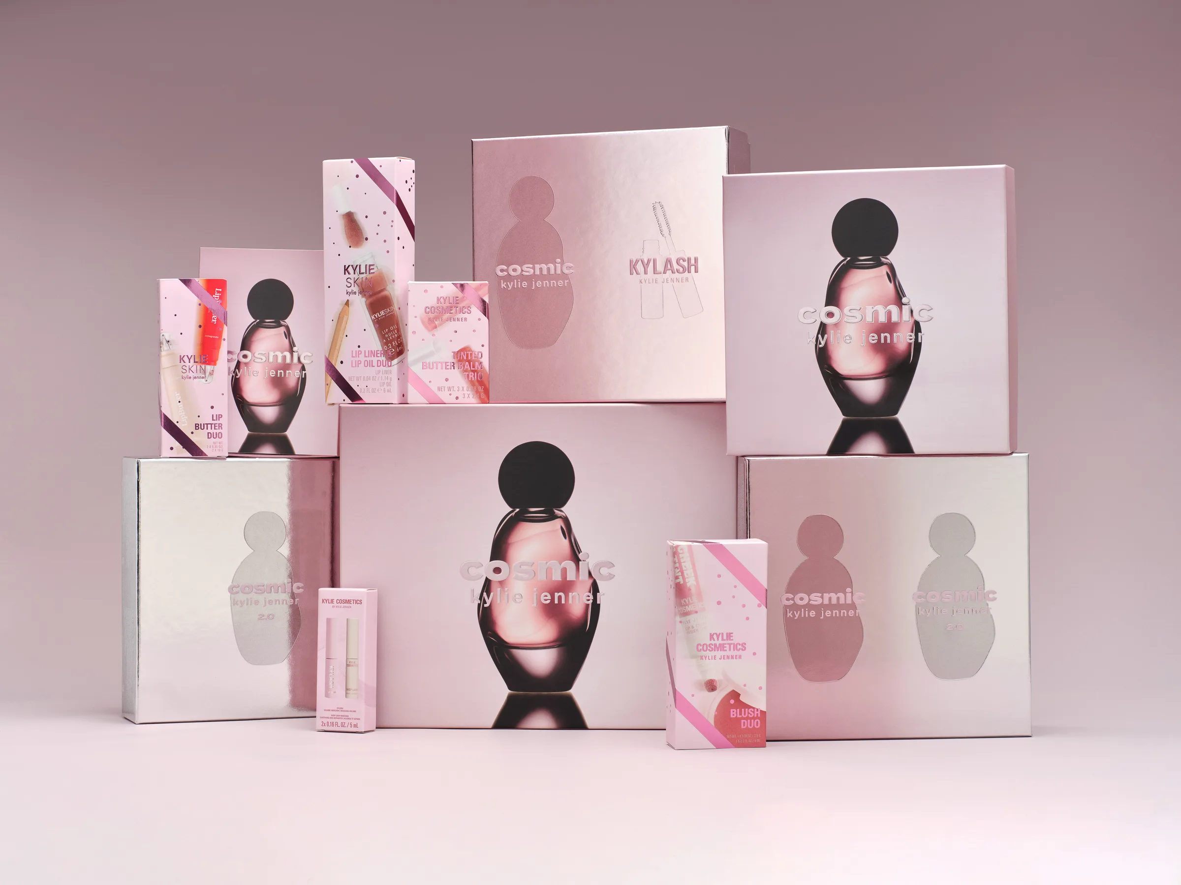 Stacked pink and silver Cosmic Kylie Jenner holiday gift boxes with lip and blush sets on a mauve backdrop, for Kylie Cosmetics.