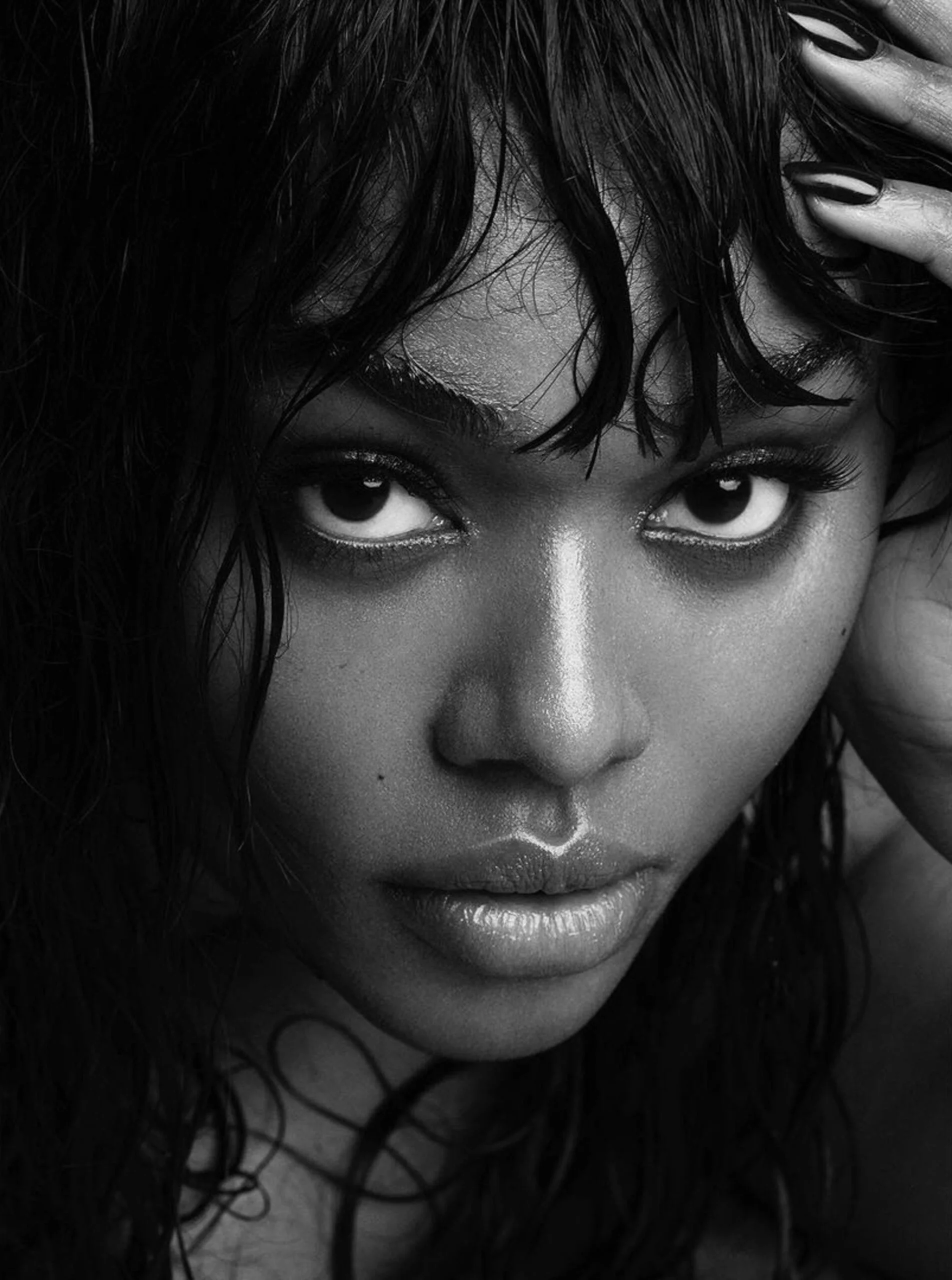 Black and white close-up portrait of a model with wet fringe, glossy skin and a hand in her hair, for V Magazine.