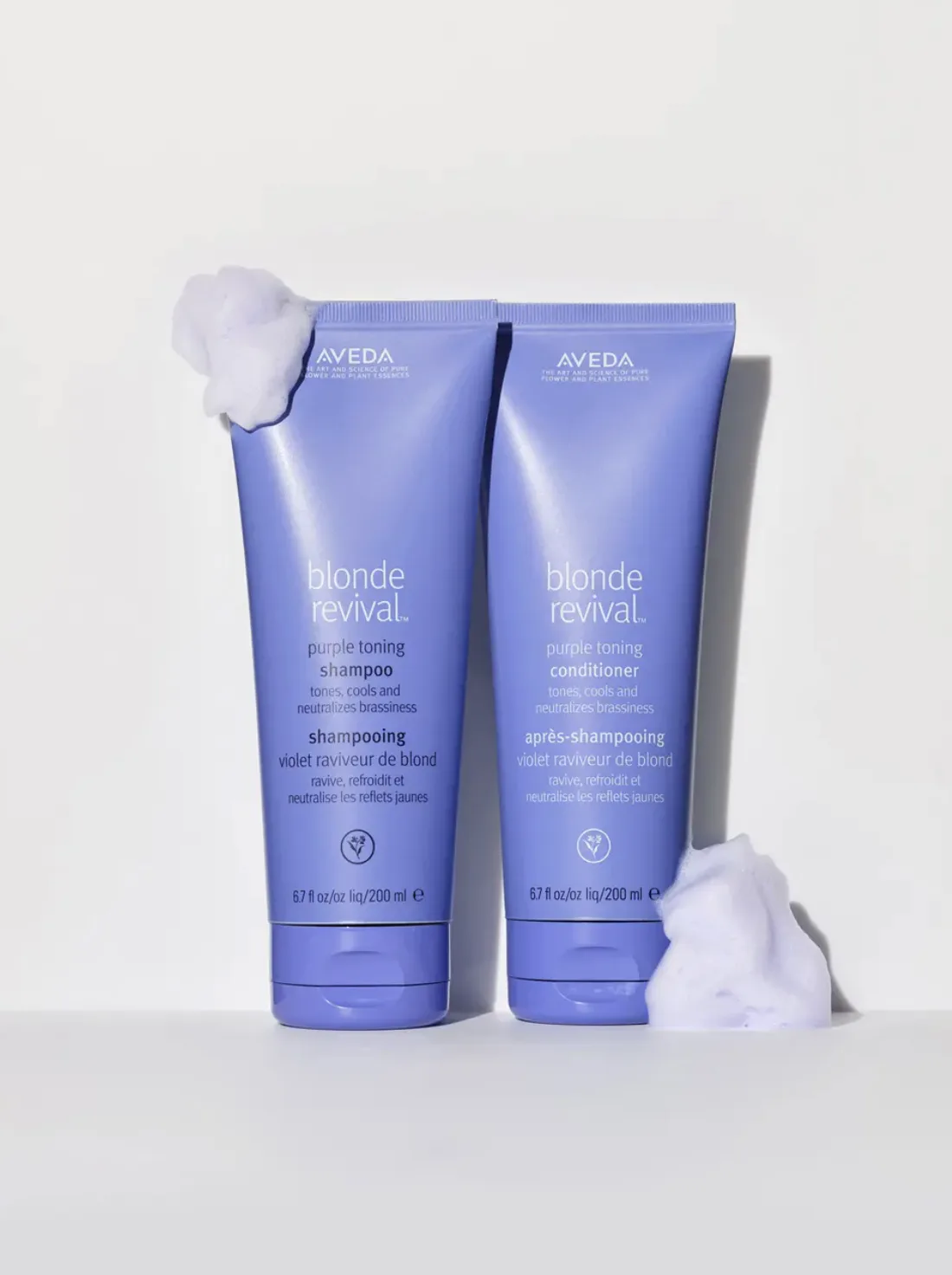 Purple Blonde Revival toning shampoo and conditioner tubes with lather on a white backdrop, for Aveda.