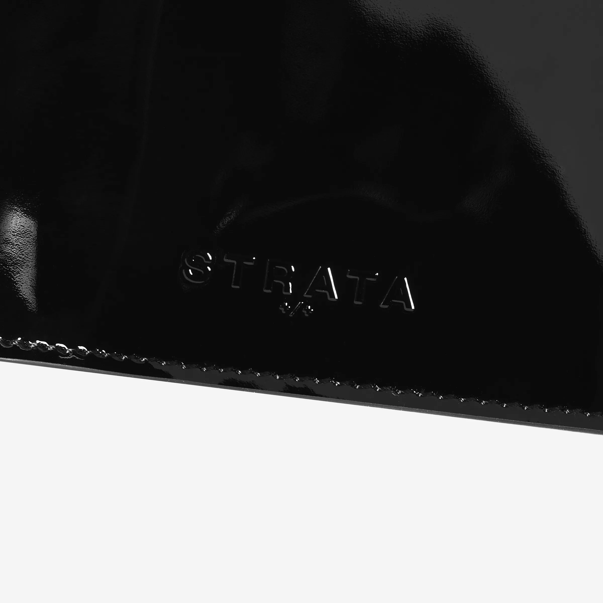 Close-up of an embossed logo on a glossy black patent leather travel sleeve with stitched edge, for Strata.