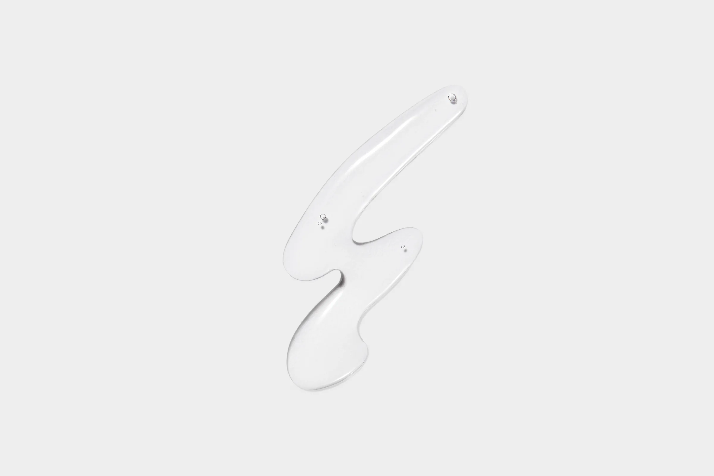 Clear gel product swatch smeared in a squiggle shape with small bubbles on a light grey background, for Costa Brazil.