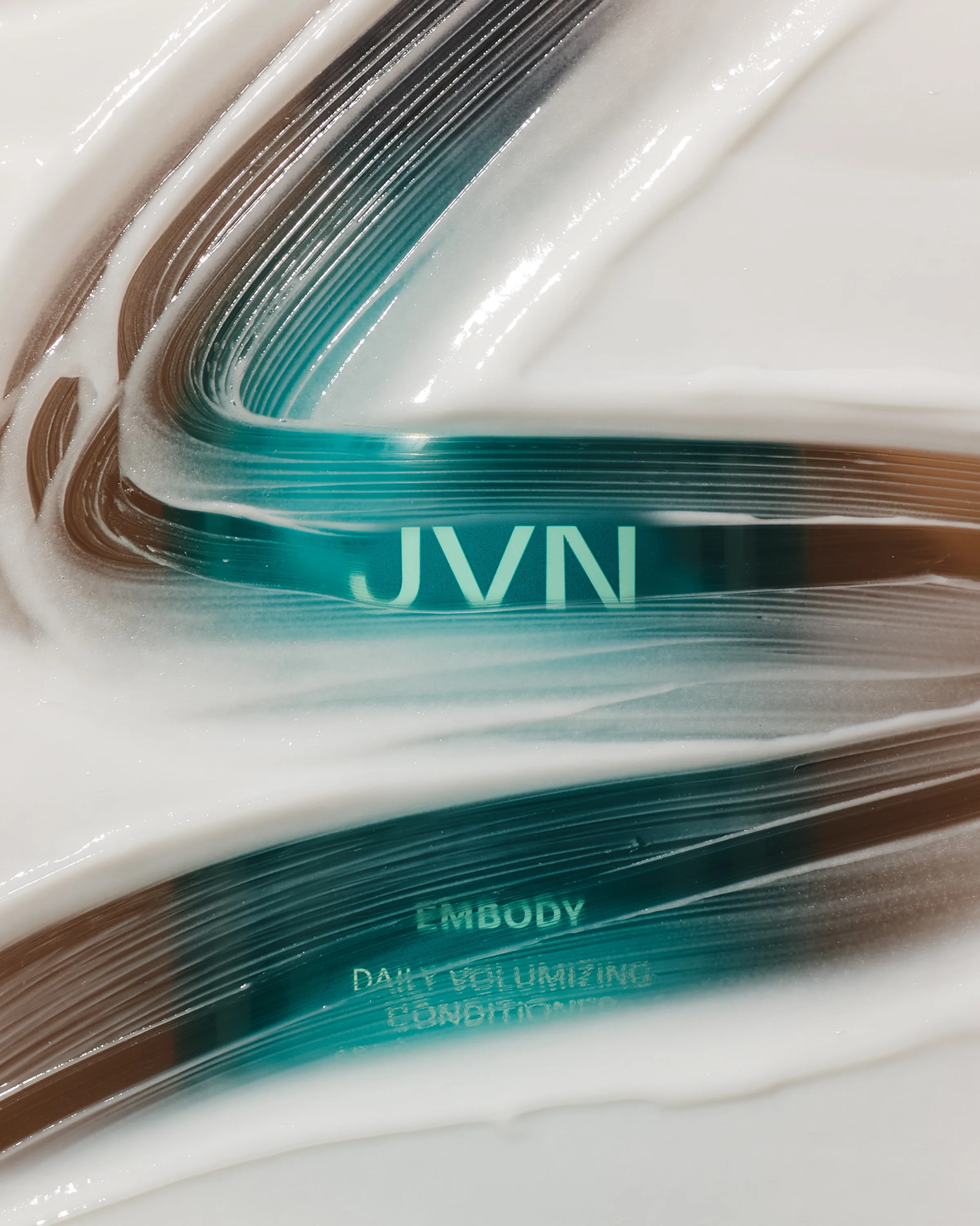 White conditioner swirled over a teal Embody Daily Volumizing Conditioner bottle with JVN logo, for JVN.