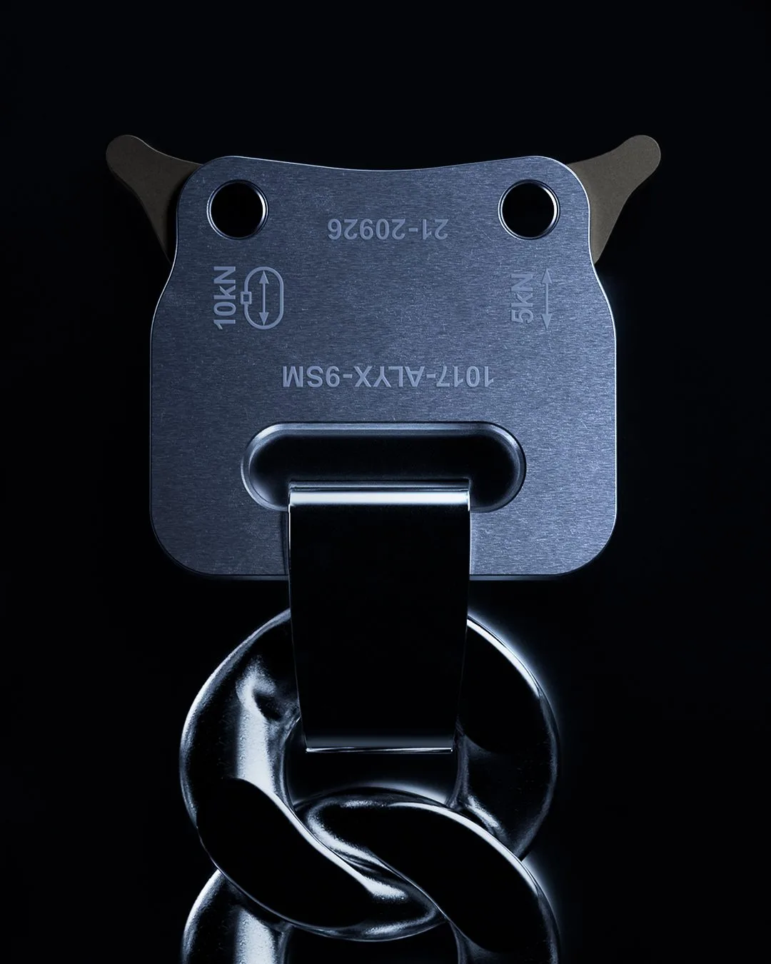 CGI render of a brushed steel rollercoaster buckle engraved 1017-ALYX-9SM on a chunky chain, on black, for 1017 ALYX 9SM.