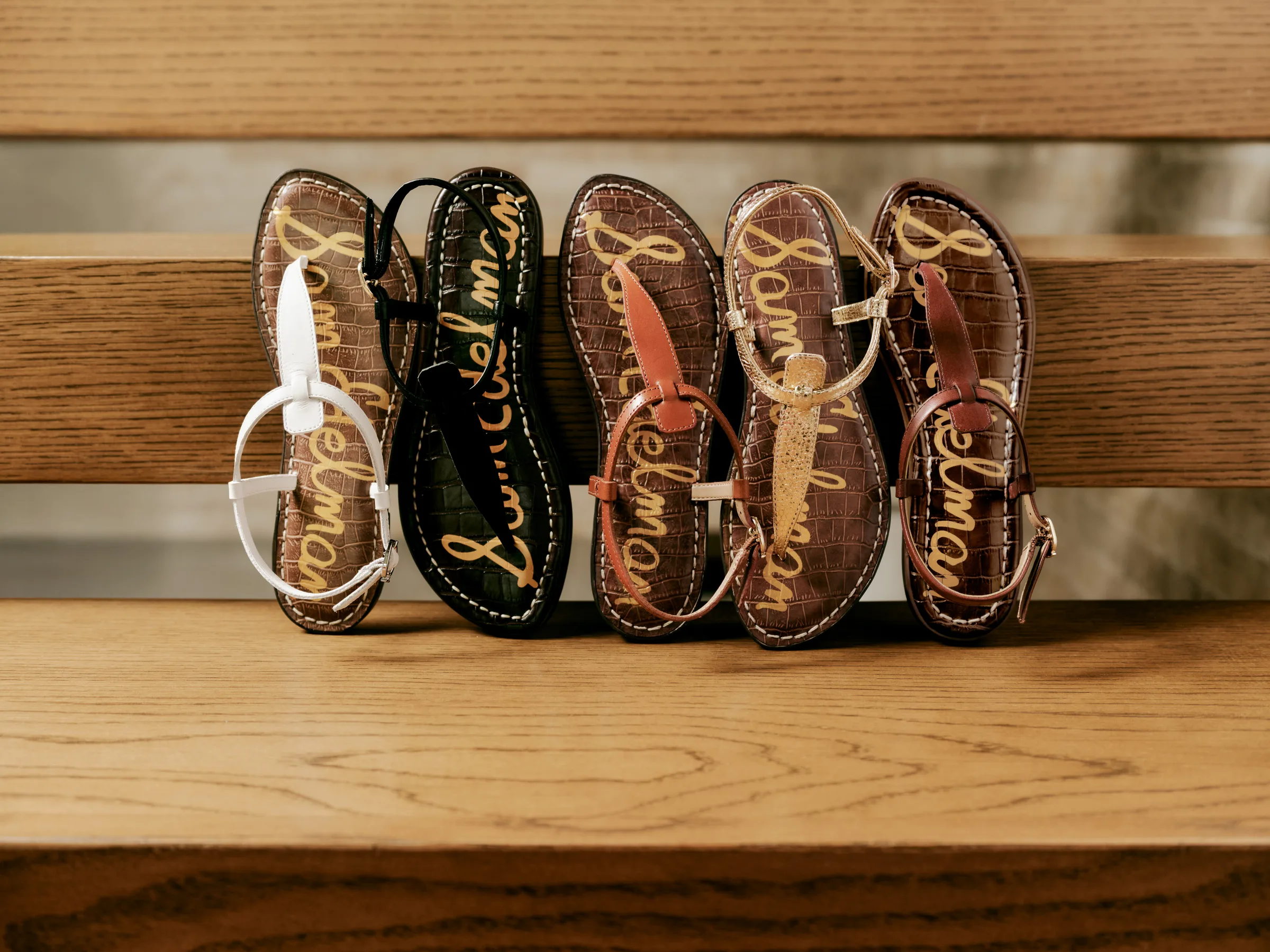 Five thong sandals in white, black, tan, gold and cognac with croc-print footbeds on wooden steps, for Sam Edelman.