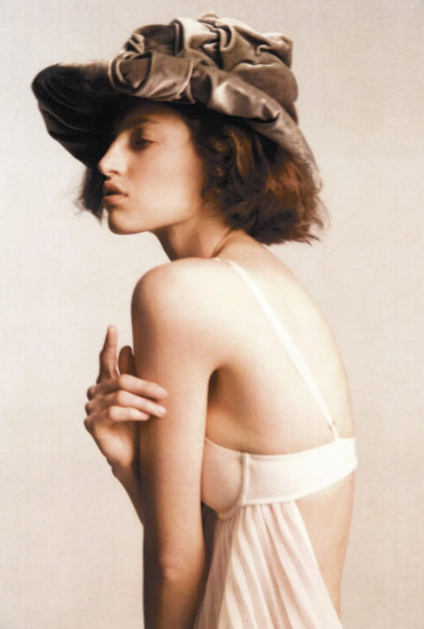 Model in a crumpled velvet hat and cream bra, posed in profile against a pale backdrop, shot by Amber Witcomb.