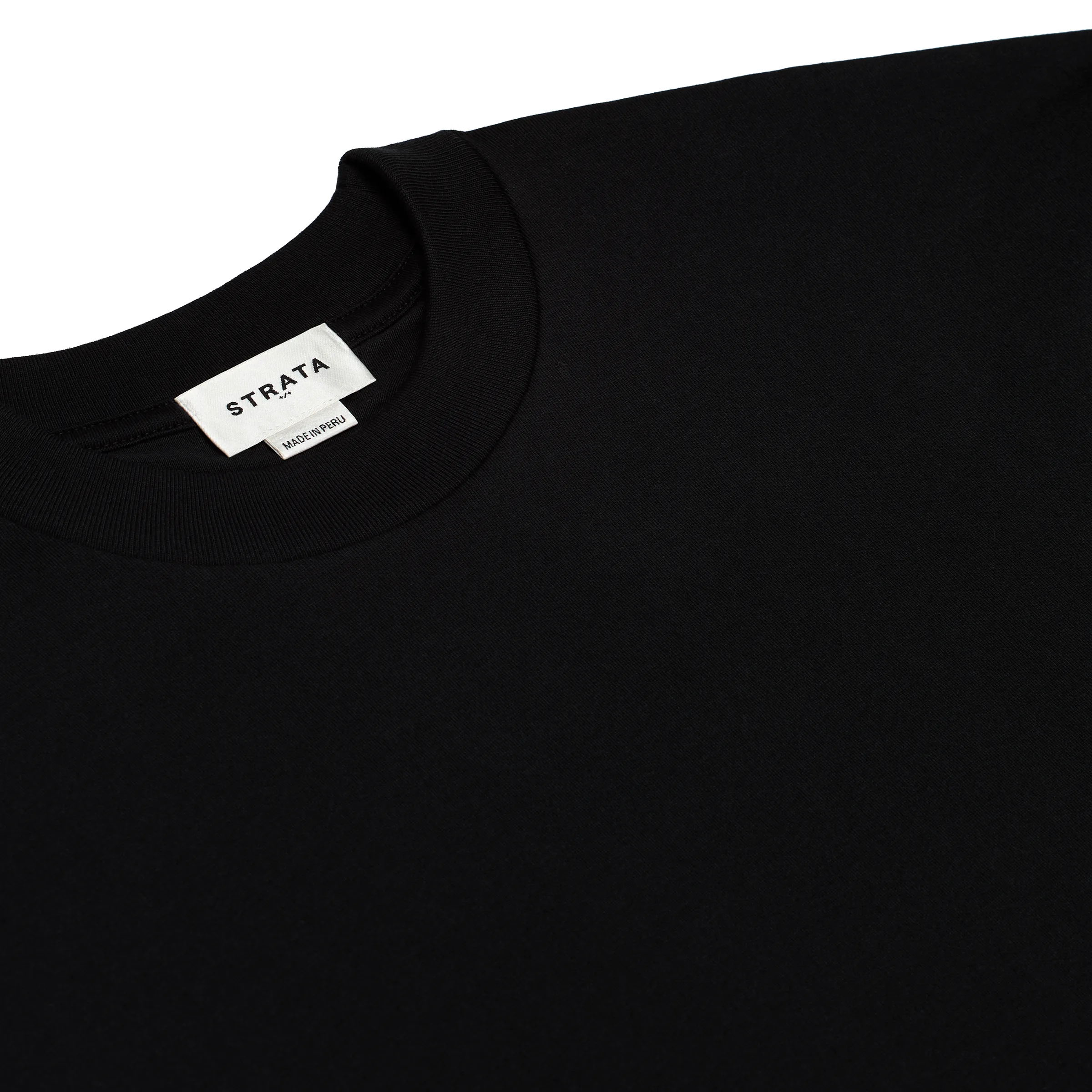 Close-up of a black crewneck tee's ribbed neckline with a white brand label reading Made in Peru, for Strata.
