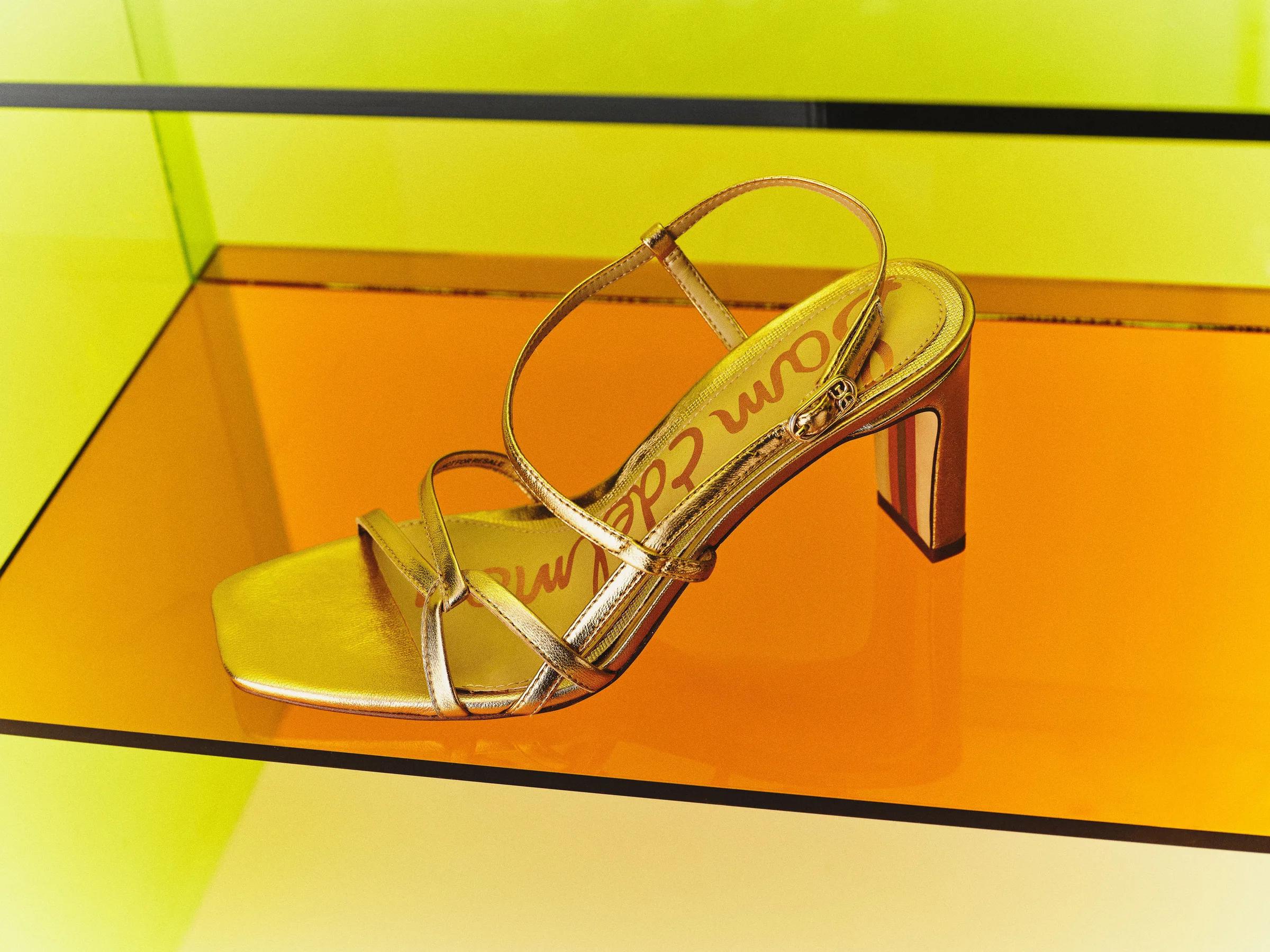 Gold metallic strappy heeled sandal on an amber acrylic shelf against a lime green backdrop, for Sam Edelman.
