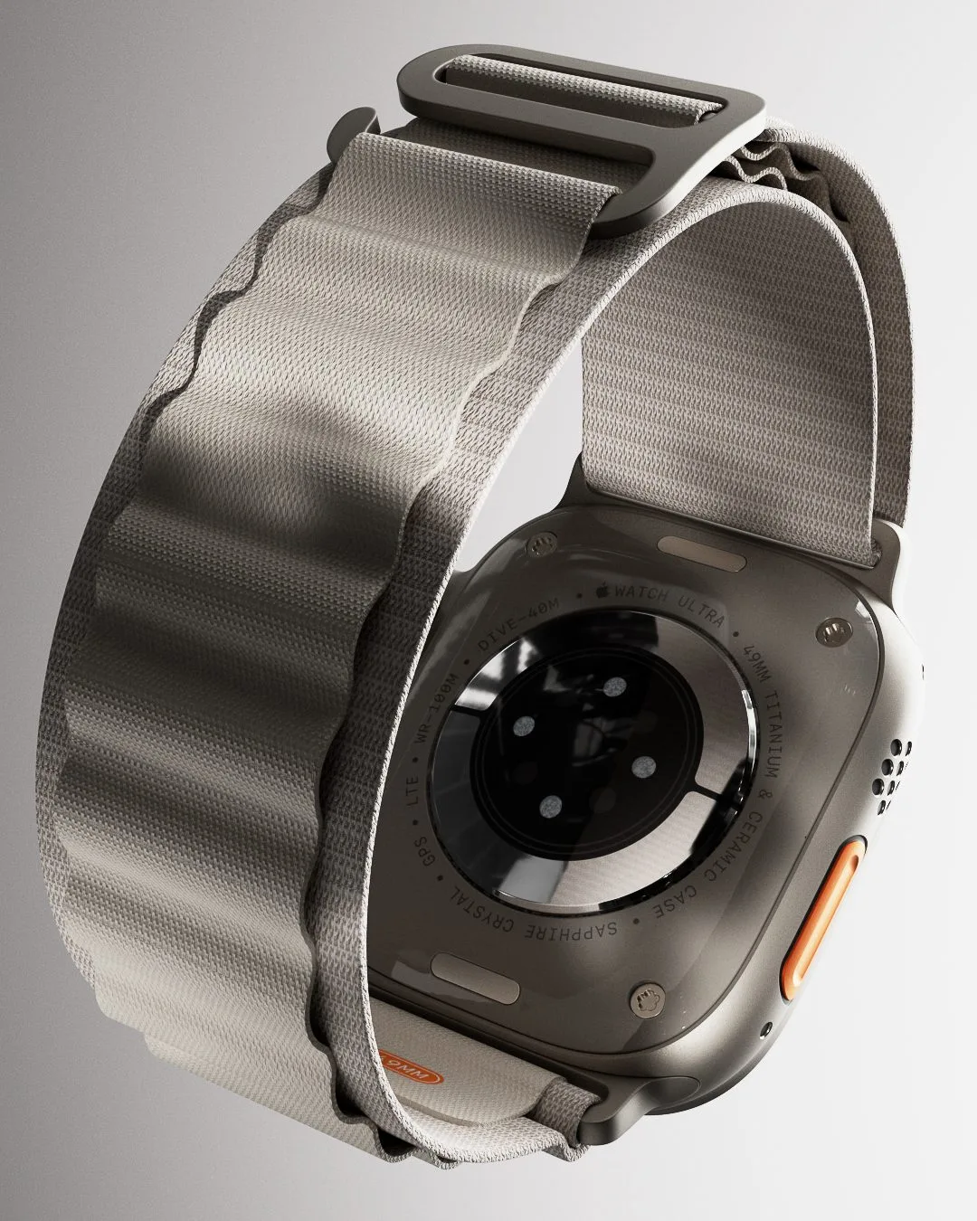 CGI render of an Apple Watch Ultra seen from the back with a grey woven Alpine Loop band and orange button, for Apple.