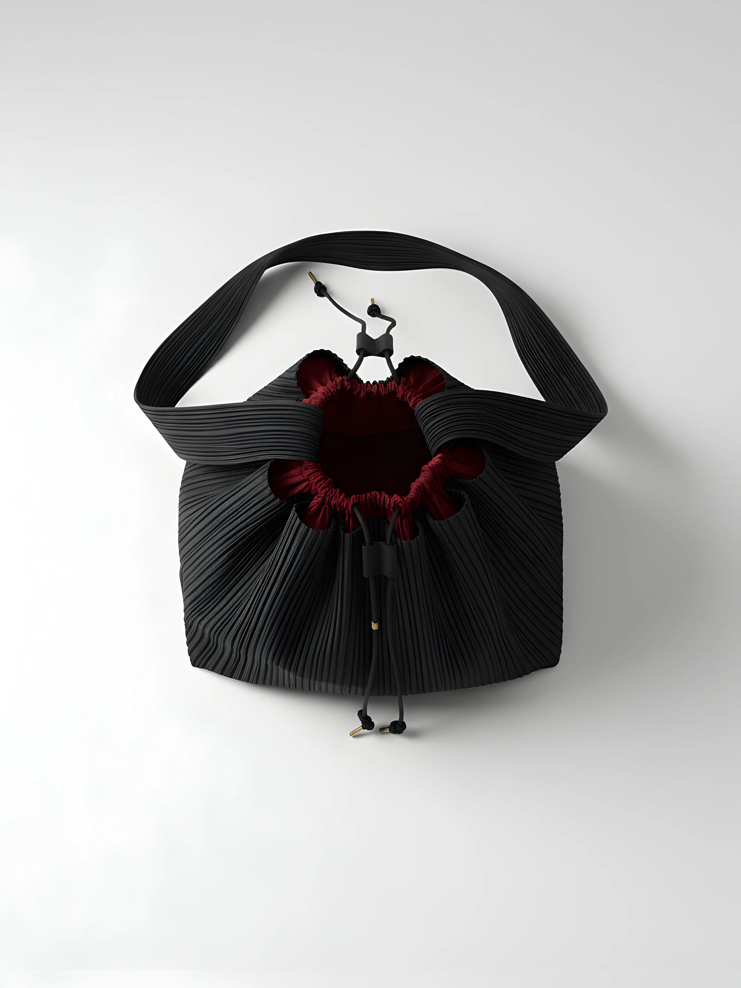 AI image of a black pleated drawstring shoulder bag with a deep red lining on a pale grey backdrop. Issey Miyake AI Concept.