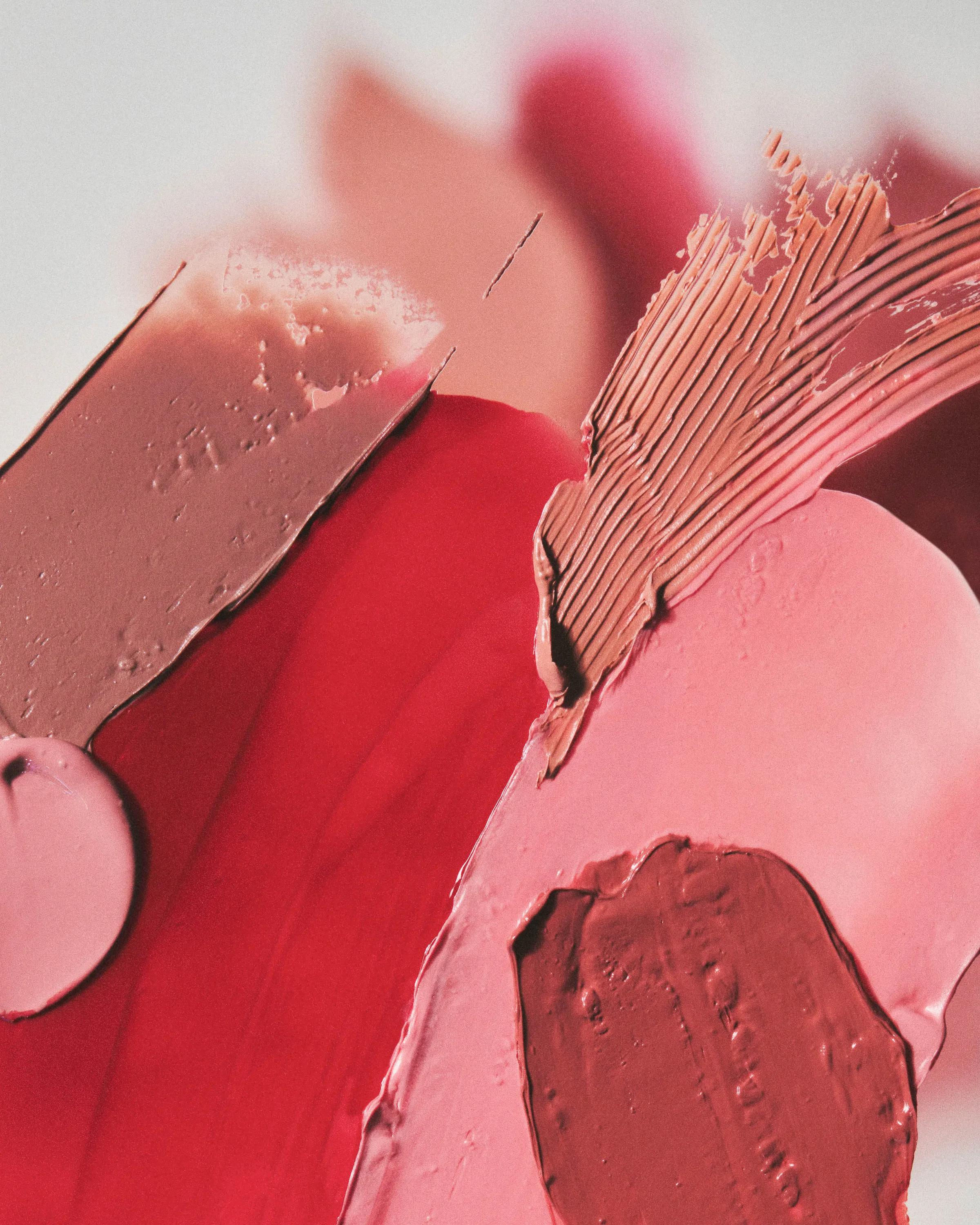Close-up of smeared lipstick and cream swatches in red, pink and nude shades, for Kylie Cosmetics.
