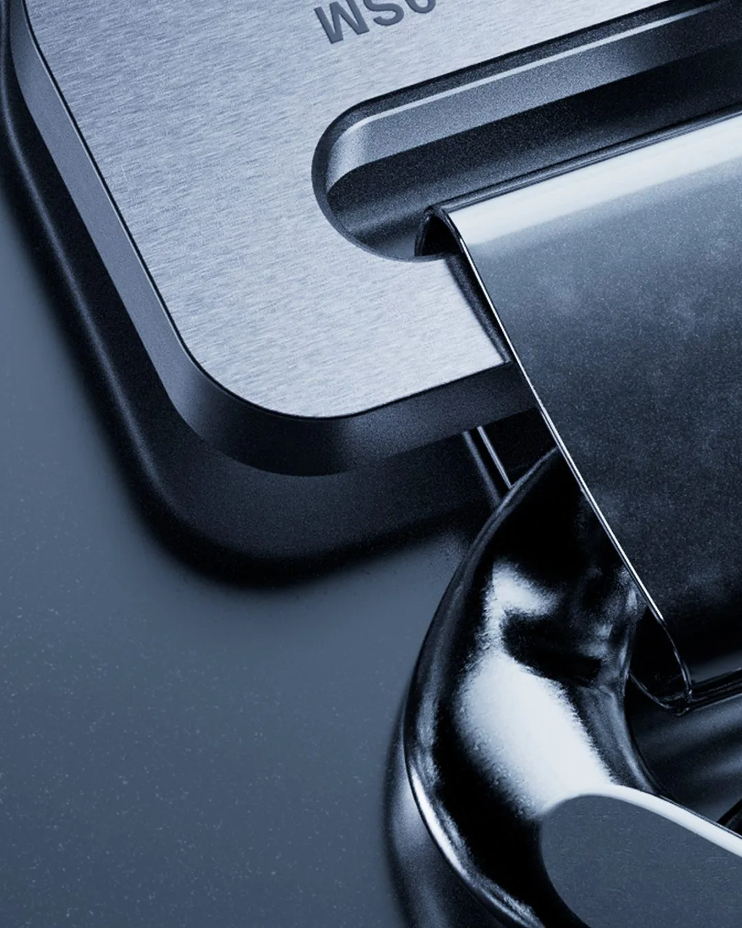 CGI render of a brushed steel buckle plate and glossy black clasp in close-up on a blue-grey surface, for 1017 ALYX 9SM.