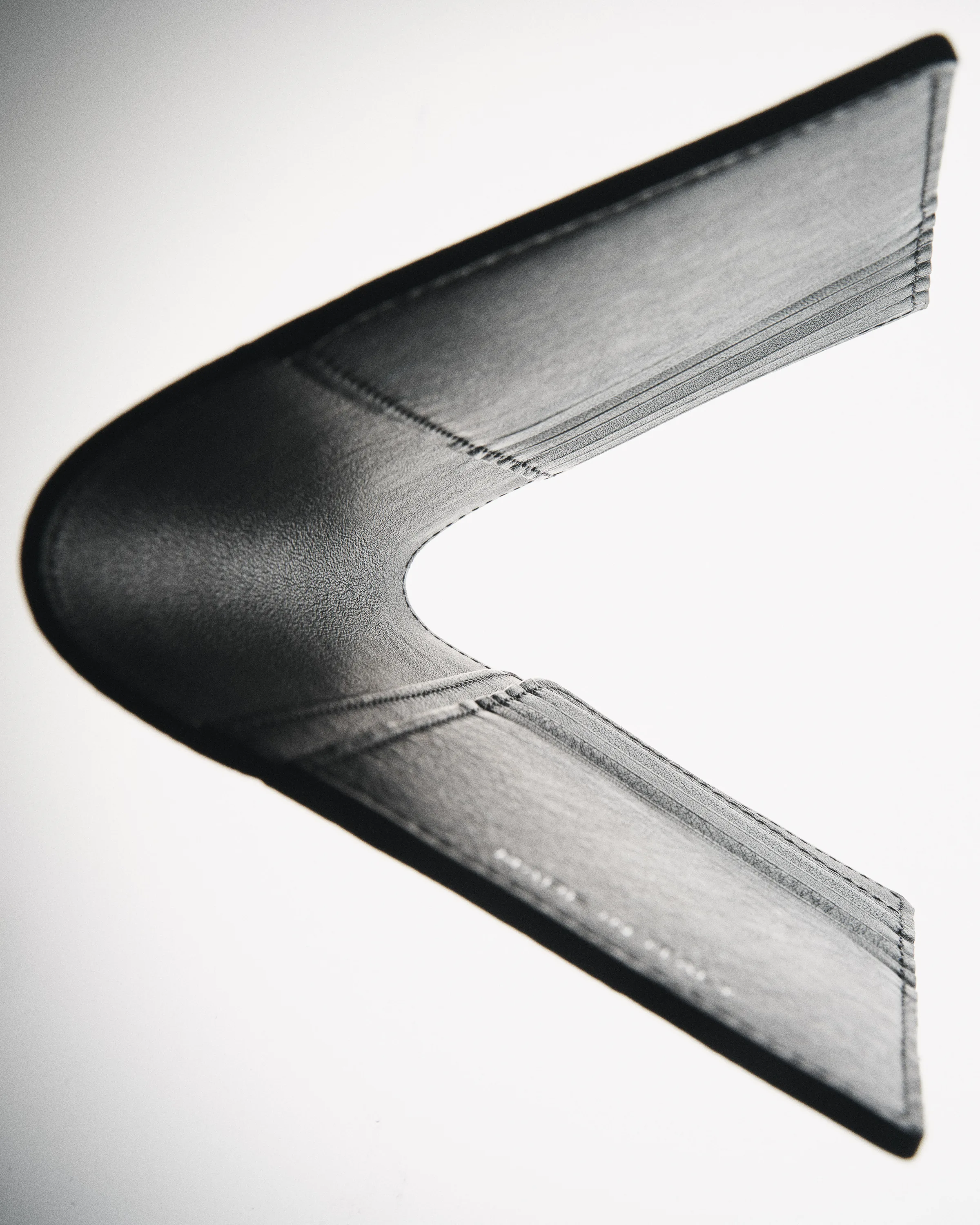 Black leather travel sleeve bent open into a V shape, lit against a white background, for Strata.
