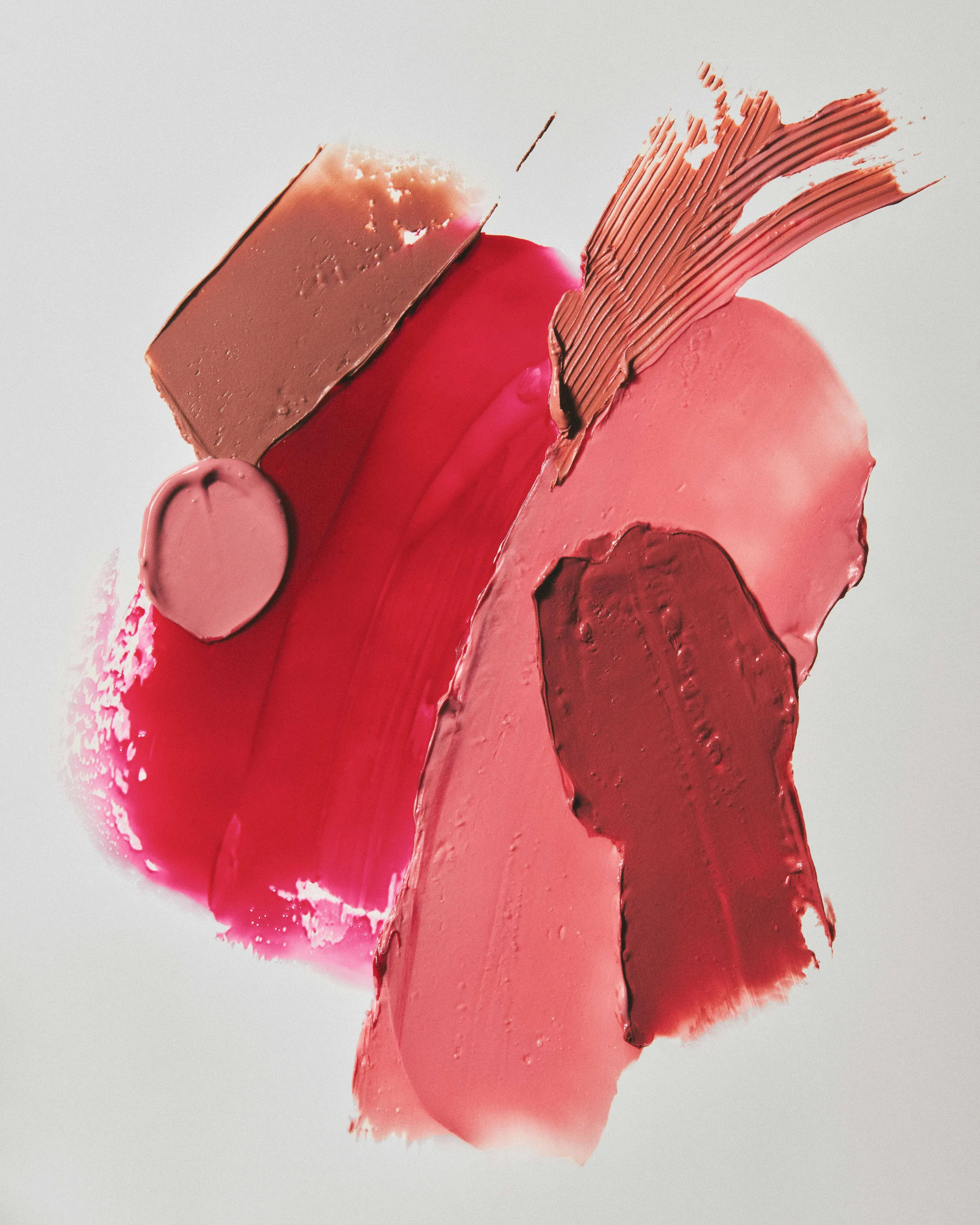 Swatches of pink, red, nude and berry lipstick smeared across a white surface, for Kylie Cosmetics.